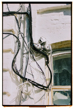 Wires and electric meters on a weathered building wall in daylight.