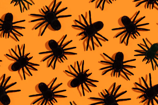 Black spiders pattern. Halloween decorations on orange background.