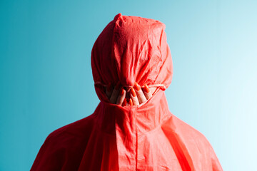 Mysterious Figure in Red Hood Against Blue Background