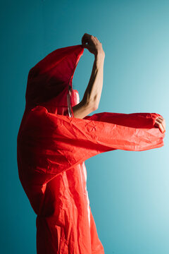 Person Wearing Bright Red Raincoat Against Blue Background