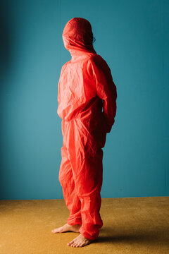 Individual in Red Protective Suit Against Blue Background