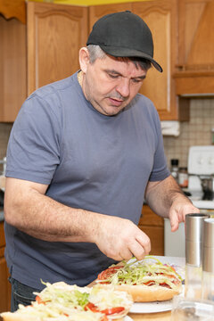 Man making a fresh, homemade sub sandwich in his kitchen