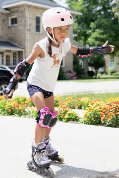 Young child with helmet and safety gear learning to inline skate
