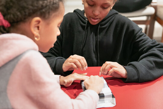 Two young sisters working together to gift wrap an item.