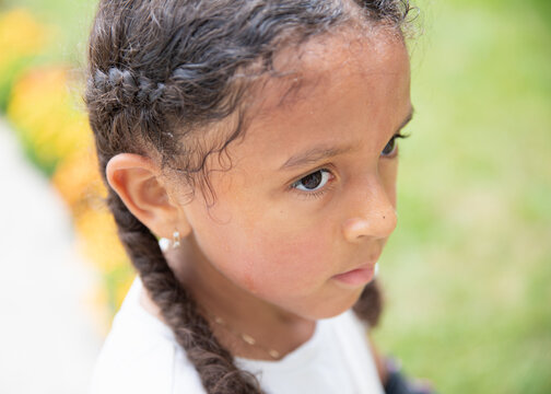 Portrait of a child with curly hair and cheeks flushed from the heat
