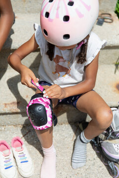Young child buckling her knee pads before she has fun roller blading