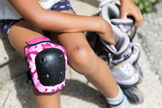 Young girl with knee pads about to put on her inline skates