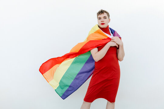Confident non binary person standing with LGBT flag