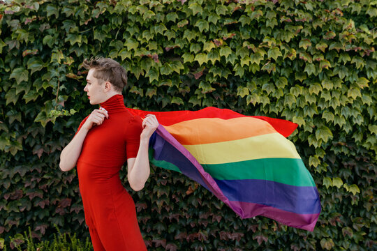 Transgender person standing with pride flag