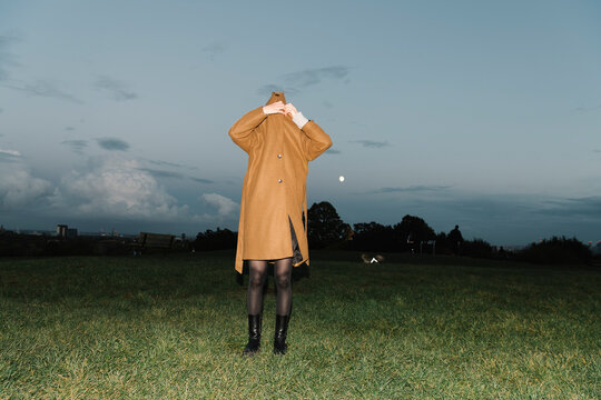 Person in Tan Coat Standing in Open Field at Dusk