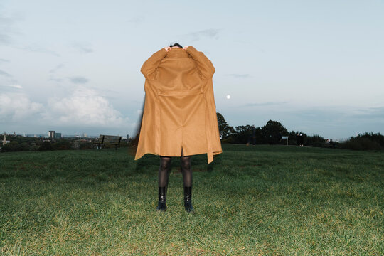 Person in Brown Coat Standing on Grass Field Outdoors