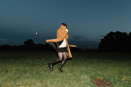 Woman Wrapped in Coat Walking Under the Evening Sky