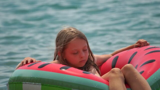 Girl Watermelon Float Summer - A young girl enjoys a relaxing day on a watermelon-shaped float in the water during the summer.