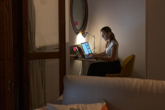 Woman working late on laptop at home office
