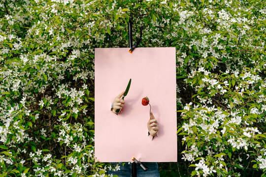 Pink poster with two cutouts showing hands with knife and fork 