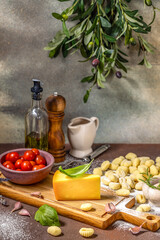 Potato gnocchi ingredients with cheese, tomato, basil and olive branch hanging