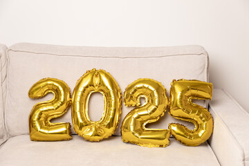Gold 2025 balloons on beige sofa

