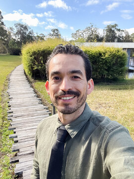 Man on wooden path in nature, dressed formally, smiling in Australia