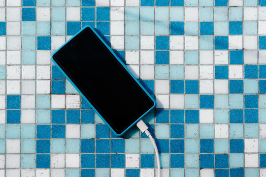 Phone charging on blue tiles