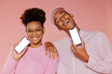 Two friends smiling and showing smartphone with blank screen