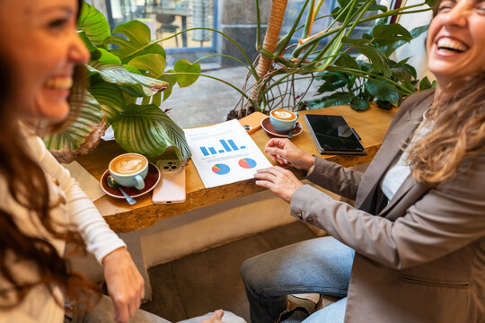 Two businesswomen analyzing financial charts and having a meeting