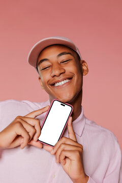 Cheerful man showing smartphone with mockup screen on pink background