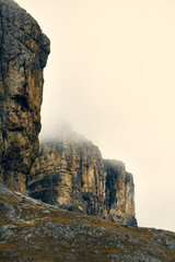 Majestic mountain cliffs covered in mist during a serene cloudy day in Dolomites