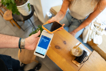 Customer paying with nfc technology on smartphone in coffee shop