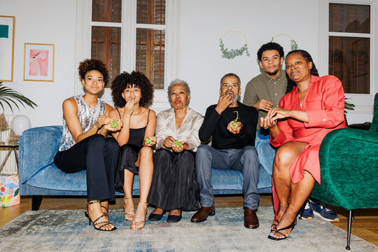 Family sitting on couch eating grapes and watching tv on New Year