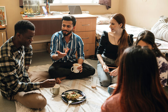 Multiracial students eating upma at the hostel room together.