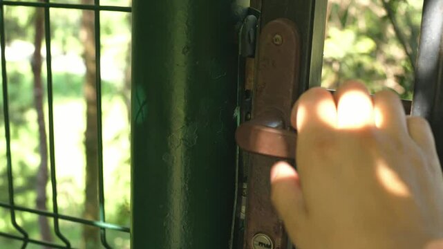 hand trying to open a garden gate, secret garden, summer, sunny day, closed gate