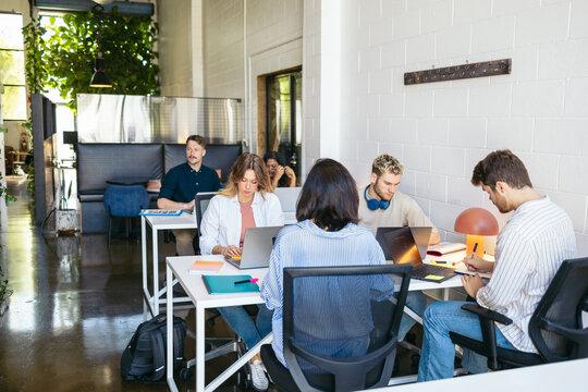 Six people working with laptop in a coworking space