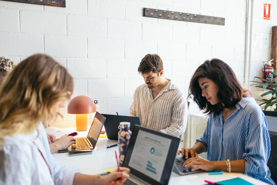 Focused teamwork working on laptop in a bright office