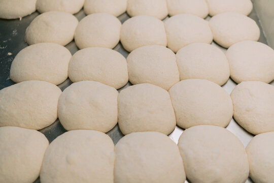 Raw dough balls on a metal surface preparing to bake