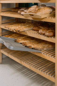 Various types of bread cooling on wooden bakery racks.