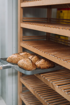 Baked bread loaves being placed onto wooden racks