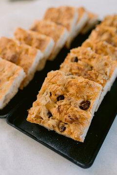 Row of focaccia slices with olives on black dish