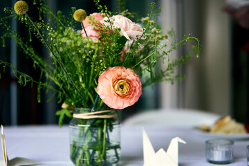 Fresh floral arrangement in a glass jar on a dining table for a cozy gathering