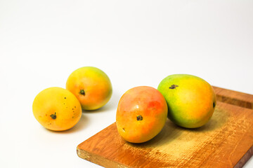 Mango fruit on cutting board isolated on white background, whole ripe yellow apple mango fruit