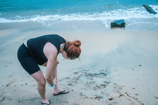 Young woman applying repellent at the beach 