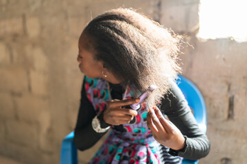 Young senegalese woman styling her hair at home in africa