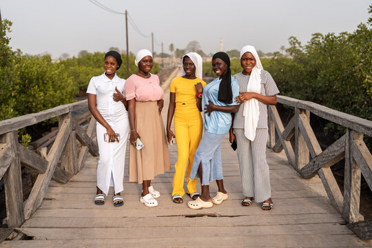 Five young senegalese women posing on a wooden bridge
