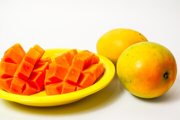 Whole and sliced ​​mango in yellow plate isolated on white background, fresh orange mango