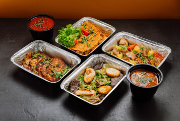 Delicious gourmet meal set in foil containers with salad and soup, ideal for catering or delivery