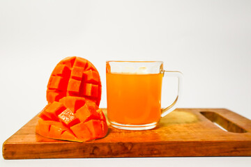 Mango juice and mango slices on a cutting board with a white background, very fresh mango juice