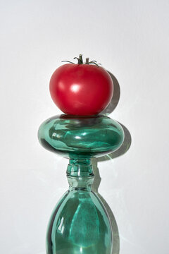 Naklejki A red tomato on a green glass bottle against a gray background.