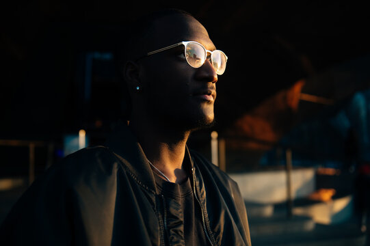 Man with glasses illuminated by warm light in a dark environment