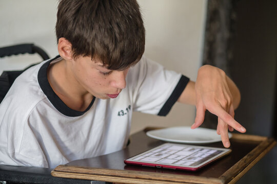 Teenage boy mobility disabilities using tablet at home