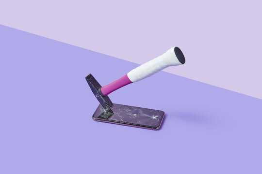 Bright hammer shattering smartphone screen glass at studio
