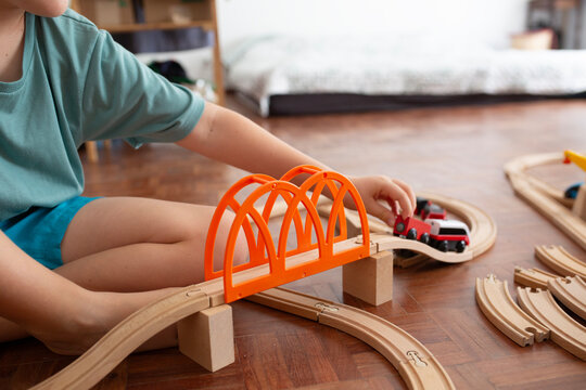 Boy playing with wooden tracks and trains